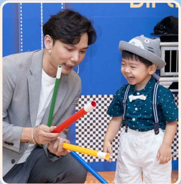 Magic Ka showing colorful magic wands to a laughing child