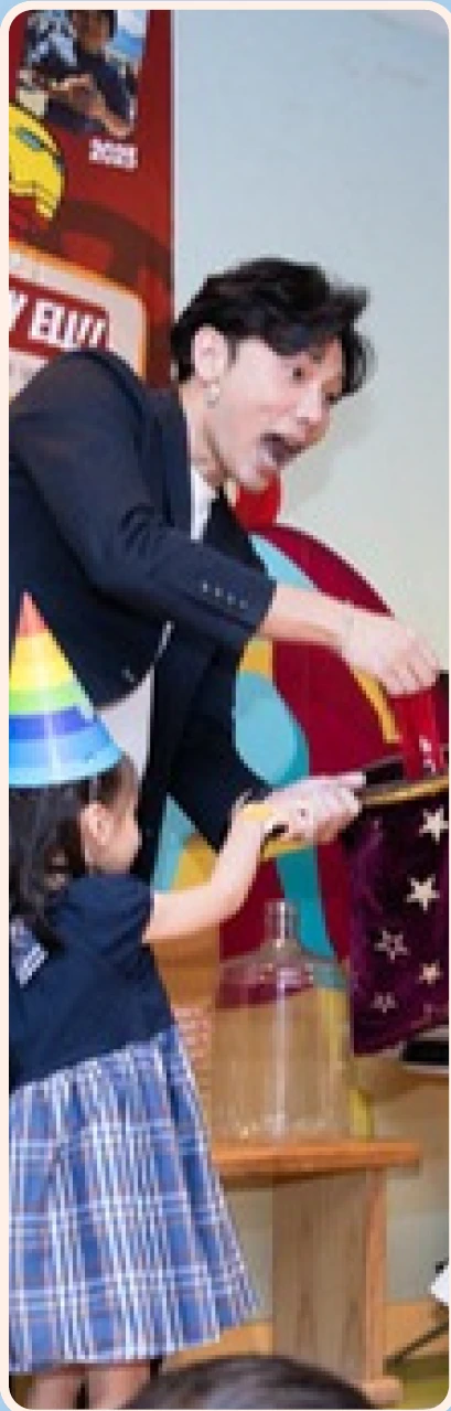 Magic Ka performing for a child in a party hat